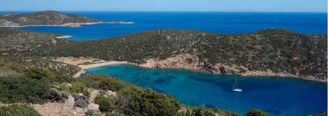 Aerial view of Fykiada hidden cove with turquoise water and a sailboat on Sifnos